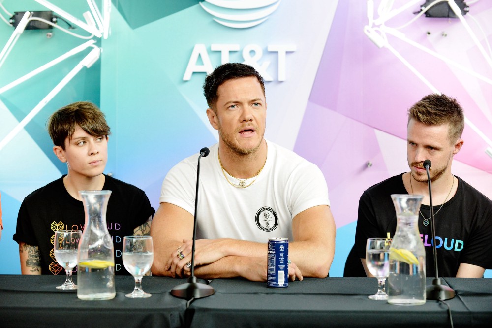 Dan Reynolds speaking at the LOVELOUD press conference in front of the AT&T backdrop, flanked by fellow organizers.