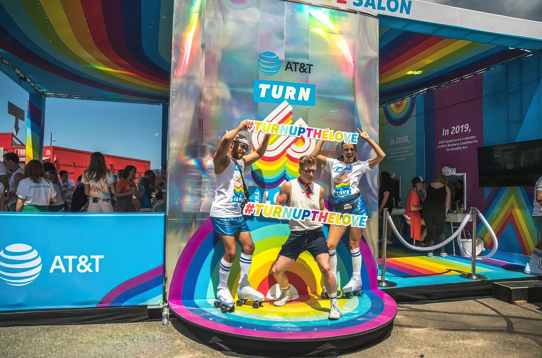 Fans pose with #TurnUpTheLove signs on a rainbow stage inside the AT&T Turn Up the Love activation