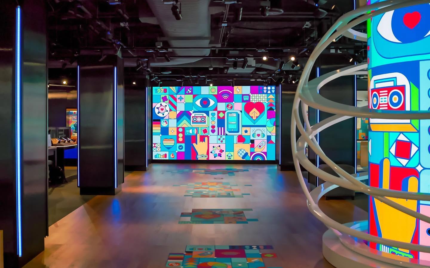 Retail corridor illuminated by a mural of Turn Up the Love iconography